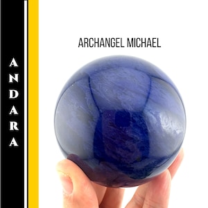 May include: A polished, deep blue sphere with swirling patterns, held in a hand. The text "ARCHANGEL MICHAEL" is above the sphere. The left side of the image has the word "ANDARA" in a vertical format.