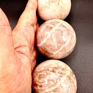 Pode incluir: Tr&ecirc;s pedras lisas, brancas e marrons, polidas, com forma de esfera. As pedras est&atilde;o empilhadas uma em cima da outra.