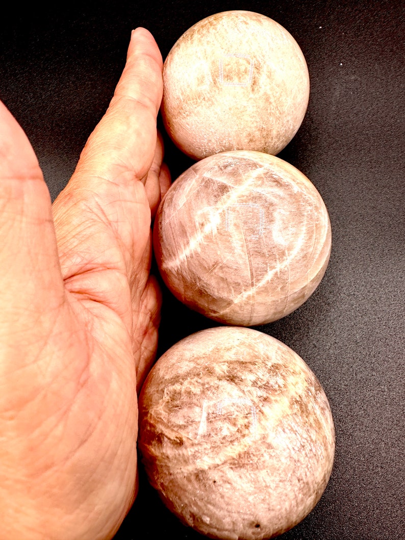 Pode incluir: Tr&ecirc;s pedras lisas, brancas e marrons, polidas, com forma de esfera. As pedras est&atilde;o empilhadas uma em cima da outra.