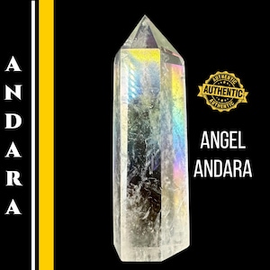 Puede incluir: Un cristal transparente, similar a un prisma, con tonos iridiscentes de arcoíris. El cristal tiene forma de obelisco alto y puntiagudo. Las palabras "ANGEL ANDARA" se muestran en texto blanco. Un sello dorado dice "AUTHENTIC".