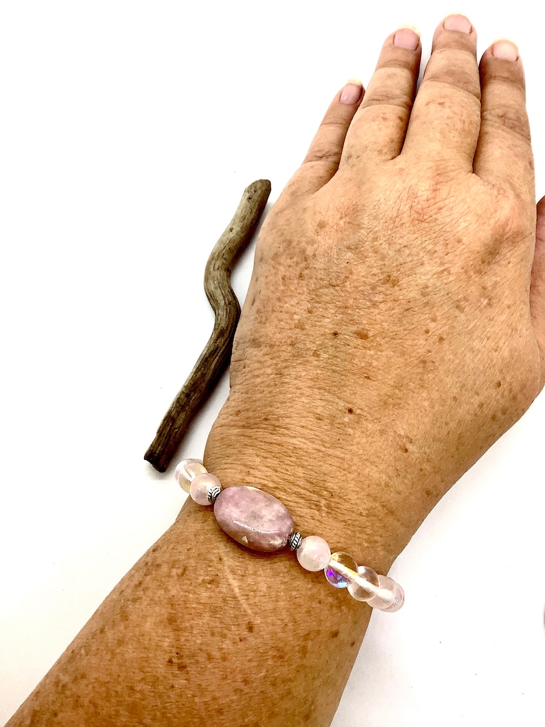 May include: A bracelet with a pink oval gemstone and clear iridescent beads.