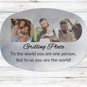 May include: A white oval ceramic serving platter with a silver metallic finish. The word "DAD" is spelled out in large letters with photos of a father and his children in each letter. The text "Grilling Plate" is written below the photos. The text "To the world you are one person, but to us you are the world!" is written below the title.