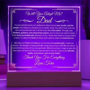 May include: A purple illuminated acrylic plaque with a white border and a message that reads "Will You Adopt Me? Dad" and a heartfelt letter expressing gratitude and love. The plaque is on a wooden base.