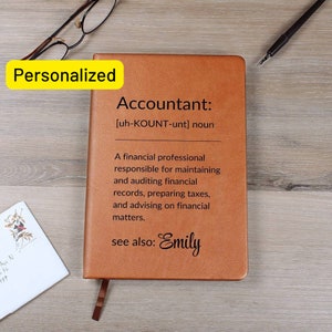 Puede incluir: Un diario de cuero marrón con la palabra "Contable" definida como un profesional financiero. El nombre "Emily" está escrito debajo de la definición.