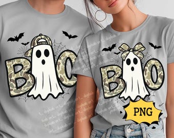 Op de afbeelding: Grijze t-shirts met een Halloween-ontwerp. De shirts tonen het woord "BOO" in camouflageprint, met een spookkarakter en vleermuizen. Eén spook draagt een hoed, de andere een strik. Een gele "PNG"-afbeelding is ook aanwezig.