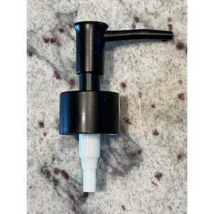 May include: Black soap dispenser pump with a white nozzle. The pump has a black handle and a black base.