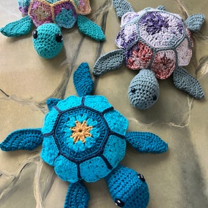 May include: Three crocheted sea turtle toys with colorful shells. The turtles are made with different colored yarn, including blue, green, purple, and pink.