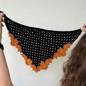 May include: Black crochet scarf with a brown crocheted bat design around the edges.