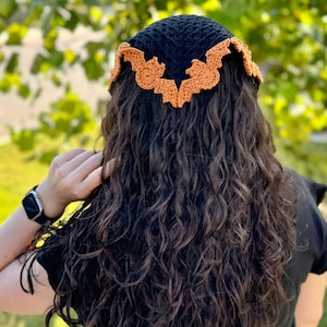 May include: A black crochet headband with orange crocheted bat wings.