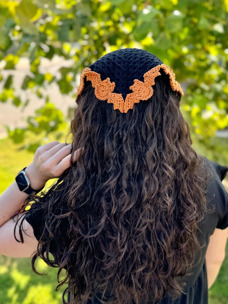 May include: A black crochet headband with orange crocheted bat wings.