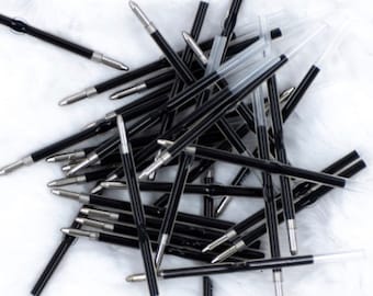 May include: A pile of black ballpoint pen refills. The refills are made of black plastic and have a silver tip.