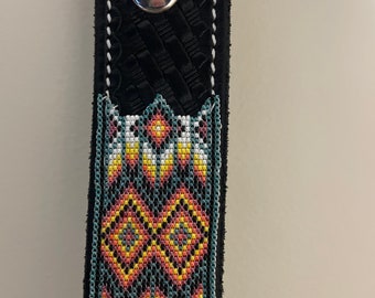 May include: A black leather belt with a beaded design. The beads are in a geometric pattern of yellow, orange, white, and teal.