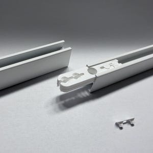 May include: White plastic curtain track components. The image shows two track sections, a connector, and a small clip. The track sections have a channel for the curtain hooks. The components are designed to connect and support curtains.
