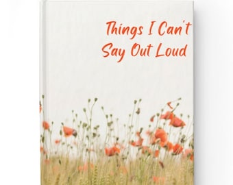 May include: A hardcover journal with the text "Things I Can't Say Out Loud" in red. The cover features a floral design with red poppies and green stems against a beige background. The journal is rectangular and has a white spine.