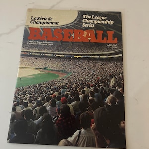 May include: A vintage baseball magazine cover featuring a photo of a packed stadium with fans watching a game. The cover text reads "La Série de Championnat" and "The League Championship Series" with the title "BASEBALL" in large red letters. The magazine is published by Montreal Expos.