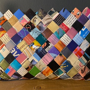 May include: A woven basket made from colorful magazine pages. The basket is woven in a diamond pattern and has a variety of colors, including blue, green, pink, and yellow.