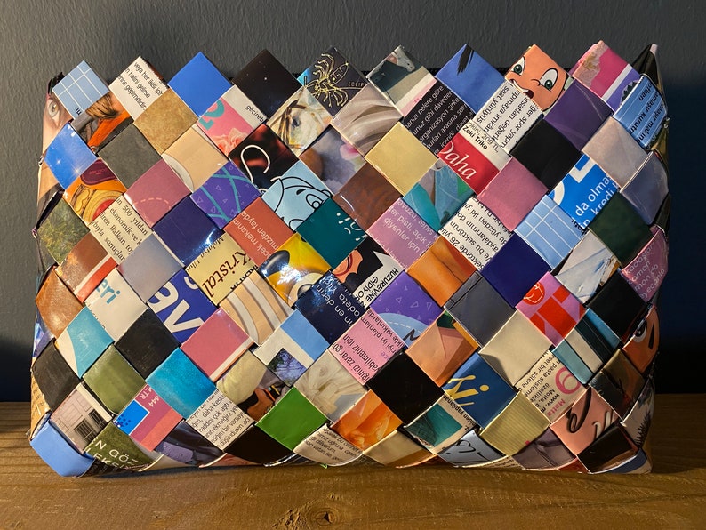 May include: A woven basket made from colorful magazine pages. The basket is woven in a diamond pattern and has a variety of colors, including blue, green, pink, and yellow.