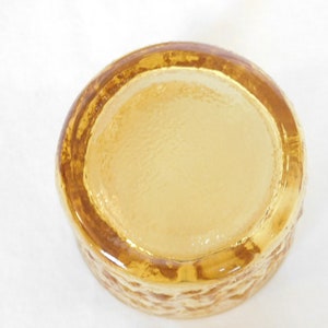 May include: A clear amber glass bowl with a textured exterior. The bowl is round and has a smooth, flat bottom.