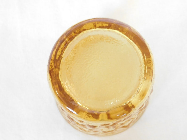 May include: A clear amber glass bowl with a textured exterior. The bowl is round and has a smooth, flat bottom.
