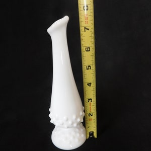 May include: White milk glass bud vase with a textured, dotted design. The vase is approximately 15 cm tall.