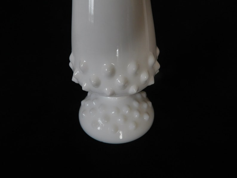 May include: White milk glass vase with a textured, bumpy surface. The vase has a wide base and a narrow neck.