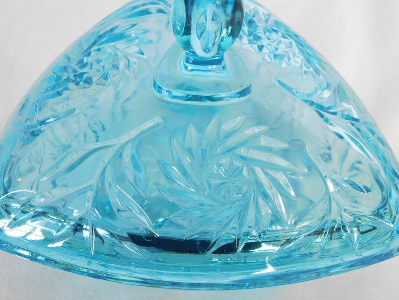 May include: A light blue glass candy dish with a swirl pattern. The dish has a lid with a knob on top.