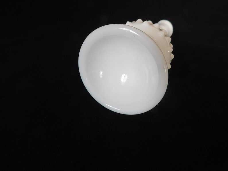 May include: White milk glass vase with a textured, knobby design. The vase has a wide, round base and a narrow neck.