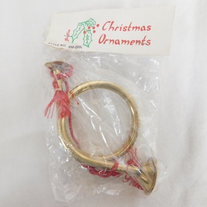 May include: A gold-colored brass Christmas ornament shaped like a hunting horn with a red tassel. The ornament is packaged in a clear plastic bag with a white label that reads "Christmas Ornaments" and "Style No. BM-299L".