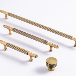 Puede incluir: Cuatro tiradores de armario de oro antiguo con un diseño acanalado y un solo pomo con un diseño acanalado.