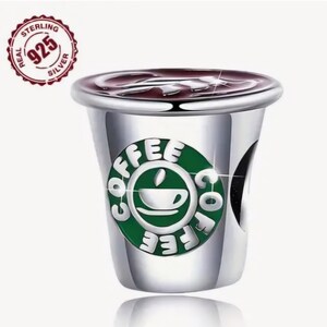 Op de afbeelding: Zilveren bedel in de vorm van een koffiebeker met een groen-wit logo met de tekst "Coffee".
