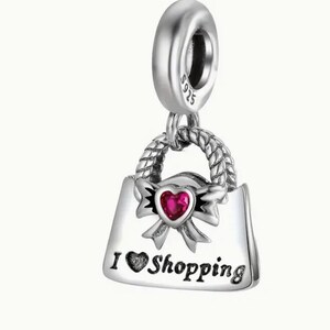 May include: Silver charm in the shape of a handbag with a red heart and the words "I love Shopping".