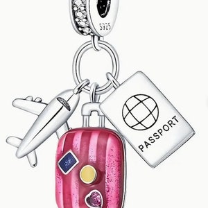 May include: Silver charm with a pink striped suitcase, a small airplane, and a passport with a globe on it. The charm has a silver loop for attaching to a bracelet or necklace.