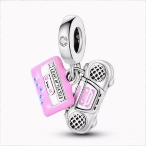 Op de afbeelding: Een zilveren bedel met een roze cassettebandje en een zilveren ghettoblaster. Het cassettebandje heeft de tekst "Heart of the 90s" erop.
