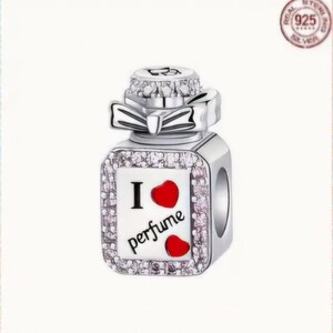 Op de afbeelding: Zilveren bedel in de vorm van een parfumflesje met een rood hart en de tekst "Ik hou van parfum".