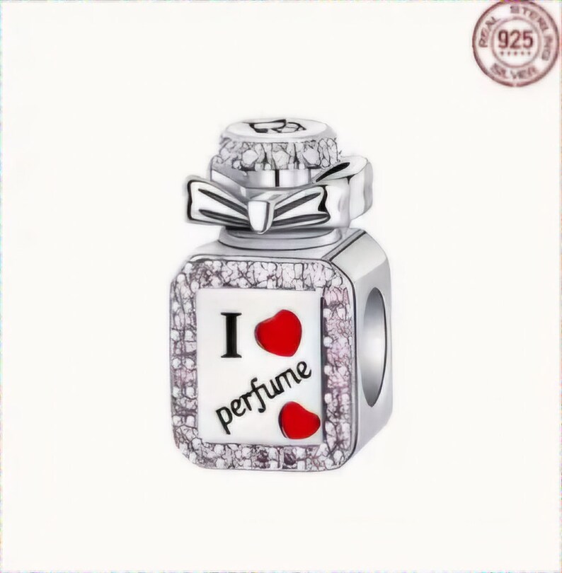 Op de afbeelding: Zilveren bedel in de vorm van een parfumflesje met een rood hart en de tekst "Ik hou van parfum".