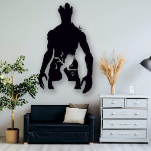 Può includere: Arte da parete in silhouette nera di una figura ad albero con una figura di albero più piccola all'interno. L'arte è montata su una parete bianca in un ambiente da soggiorno con un divano nero, una pianta in vaso, una cassettiera e una lampada da terra.