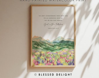Könnte beinhalten: Handgemachter Aquarelldruck in einem Holzrahmen. Das Kunstwerk zeigt eine Landschaft mit Bergen, einem Feld bunter Blumen und Text. Der Text lautet: "Die Güte des Herrn hat kein Ende...Groß ist deine Treue."