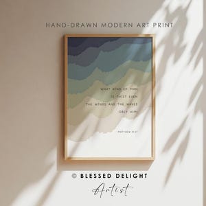 May include: A framed art print featuring layered, wavy bands of color transitioning from dark blue to light beige. The text reads: WHAT KIND OF MAN IS THIS? EVEN THE WINDS AND THE WAVES OBEY HIM! MATTHEW 8:27. The print is displayed in a light wood frame.