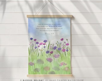May include: A watercolor print featuring a field of purple and pink flowers with green foliage. The artwork includes the text "And we know that in all things God works for the good of those who love Him..." and "Romans 8:28."