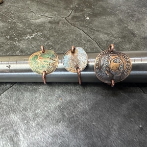 May include: Three antique coin rings with copper wire settings. The rings feature a bird, a design with blue and green accents, and a profile of a person's face.