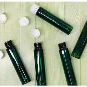 Puede incluir: Seis botellas de vidrio verde con tapas blancas. Las botellas están sobre una superficie de madera verde claro.
