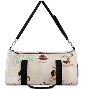 May include: White yoga lover duffel bag with black straps and a colorful print of women in yoga poses. The print includes the words "Yoga Lover", "Peace", "Balance", and "Tranquility".