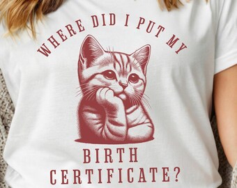 May include: White t-shirt with a red graphic of a cat thinking with the text "Where did I put my birth certificate?"