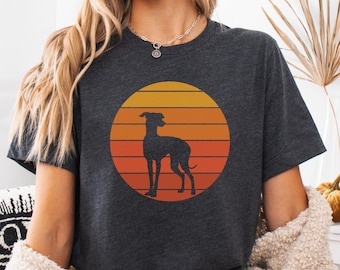 May include: Dark gray t-shirt featuring a silhouette of a dog inside a sunset circle. The sunset design has horizontal stripes of orange and yellow. The shirt is a casual style, suitable for everyday wear.