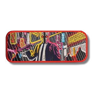 Puede incluir: Parche bordado con una figura estilizada colorida en un traje negro con una máscara facial roja y amarilla. La figura está rodeada de un fondo abstracto vibrante con formas geométricas y líneas.