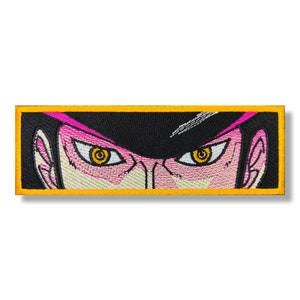 May include: Embroidered patch with a close-up of a character's face. The character has black hair, pink skin, and yellow eyes. The patch has a yellow border.