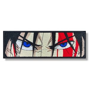 May include: Close-up of a character's face with blue eyes and a red slash across the forehead. The character has black hair and a serious expression.