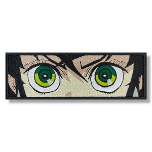 Puede incluir: Primer plano de un par de ojos verdes con pupilas amarillas, mirando directamente al espectador. Los ojos están rodeados de cabello negro y una cara marrón claro.