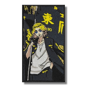 May include: An embroidered patch featuring a blonde-haired anime character holding a flag with Japanese text. The flag is yellow and black with the text "東卍" in yellow. The character is wearing a black jacket and white shirt.