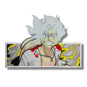 Puede incluir: Parche bordado con un personaje de anime sonriente con cabello blanco y un sombrero de paja. El personaje tiene detalles rojos y una chaqueta blanca. El fondo tiene detalles amarillos y grises. El parche es rectangular con un borde blanco.